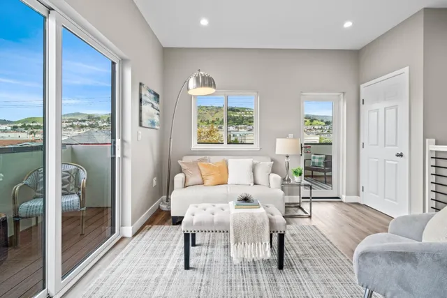 a living room with furniture large window and wooden floor