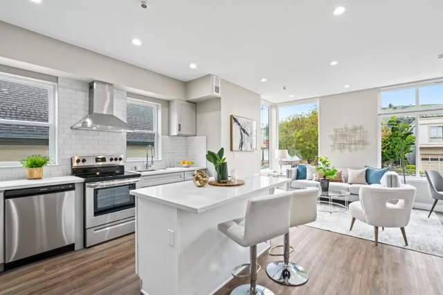 a kitchen with stainless steel appliances kitchen island granite countertop a stove a sink dishwasher and white cabinets with wooden floor