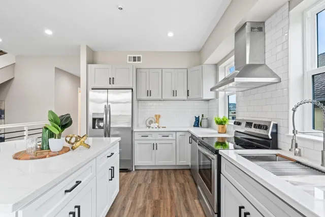 a kitchen with stainless steel appliances a sink a stove top oven a refrigerator a counter space and cabinets