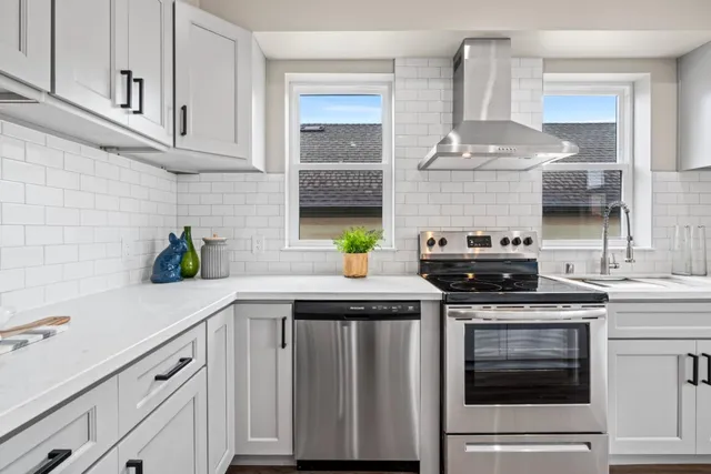 a kitchen with stainless steel appliances a stove and white cabinets