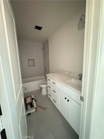 a bathroom with a tub sink vanity granite and toilet
