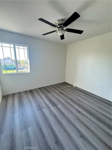 an empty room with wooden floor fan and windows