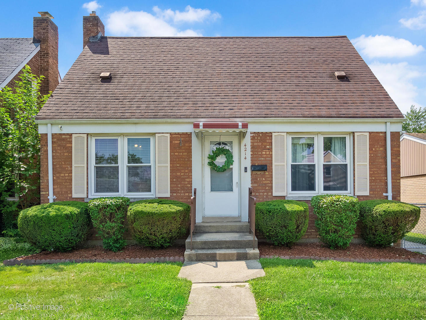 a front view of a house with a yard and potted plants