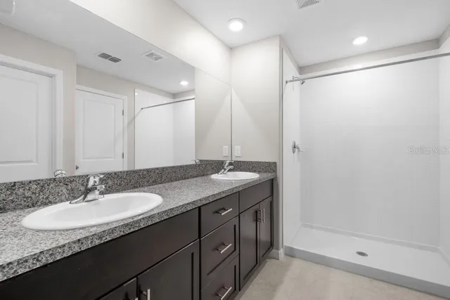 a bathroom with a granite countertop sink a shower and a mirror