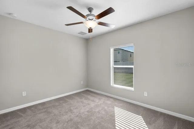an empty room with a window and a ceiling fan