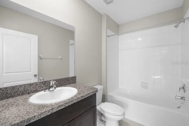 a bathroom with a granite countertop sink toilet mirror and shower