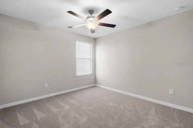 an empty room with a window and a fan