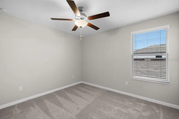 an empty room with a window and a ceiling fan