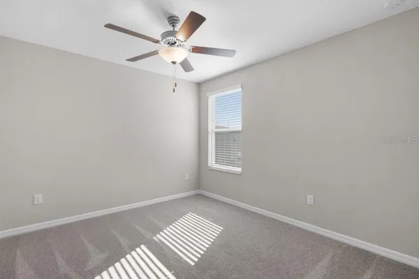 an empty room with a chandelier fan and windows