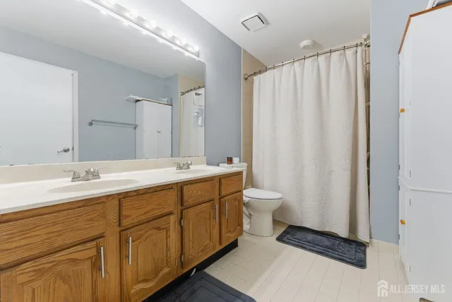 a bathroom with a double vanity sink toilet and a mirror