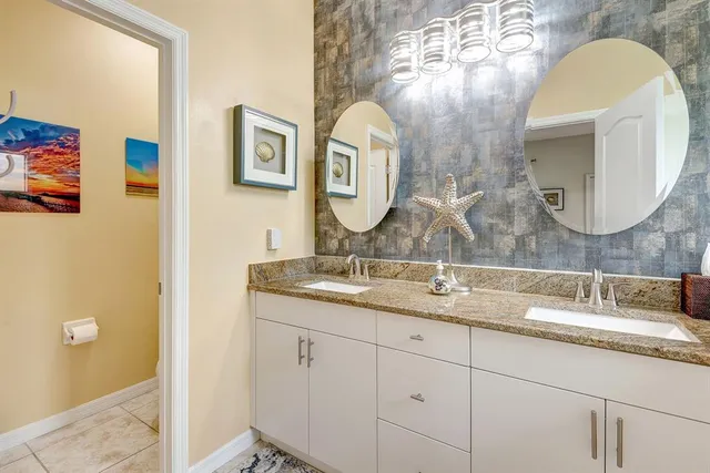 a bathroom with a granite countertop double vanity sink and a mirror