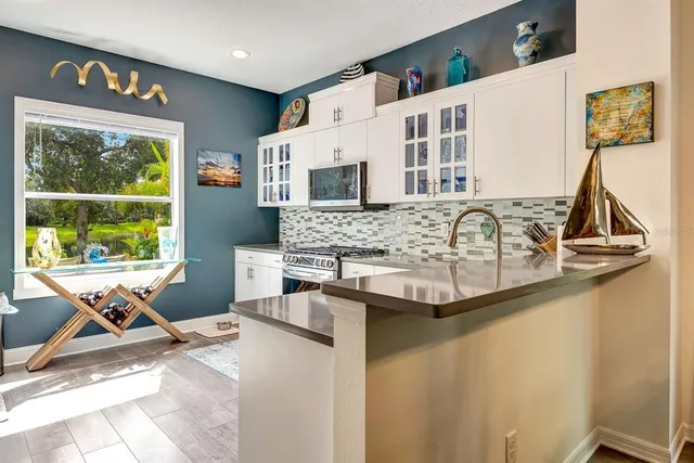a view of kitchen with stainless steel appliances granite countertop sink and a microwave
