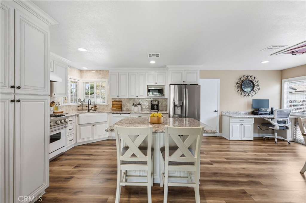 27816 Ridgegrove Drive Saugus, CA 91350 - Photo 18 of 65 a kitchen with stainless steel appliances a dining table chairs stove refrigerator and cabinets