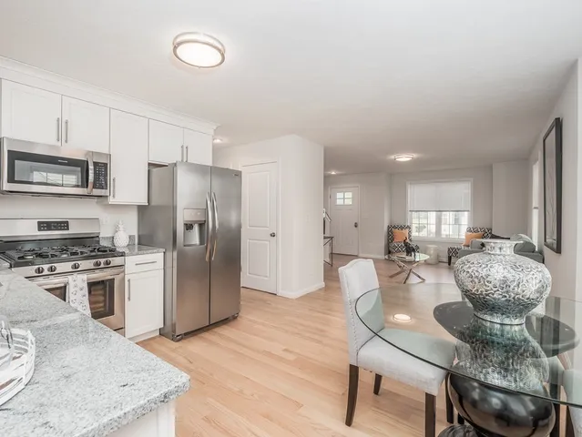 a kitchen with stainless steel appliances granite countertop a stove refrigerator and a view of living room