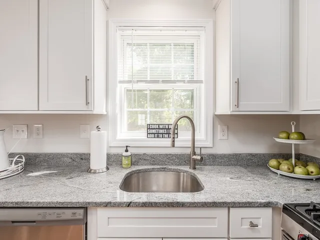 a kitchen with granite countertop a sink a window and cabinets