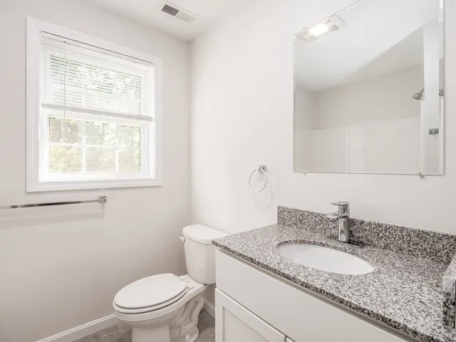 a bathroom with a granite countertop toilet a sink and a mirror