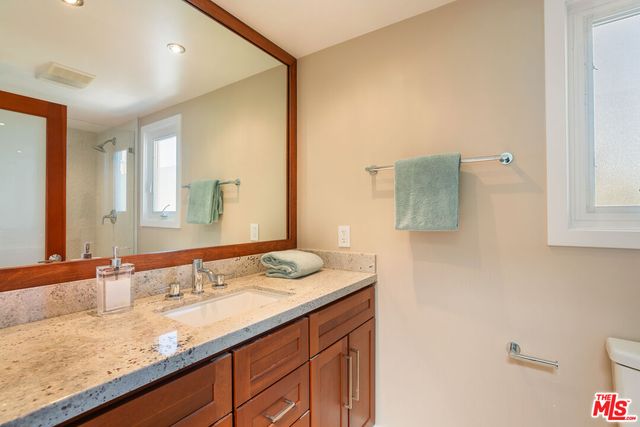 a bathroom with a granite countertop sink a toilet and shower