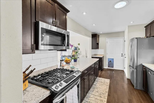 a kitchen with stainless steel appliances kitchen island granite countertop a stove and a refrigerator