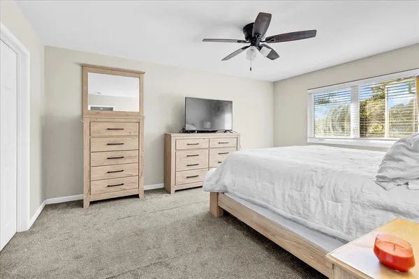 a spacious bedroom with a bed a dresser and a chandelier