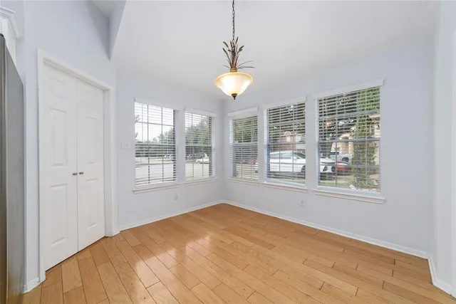 a view of an empty room with a window and wooden floor