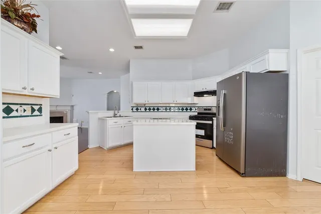 a kitchen with granite countertop a refrigerator and a stove top oven