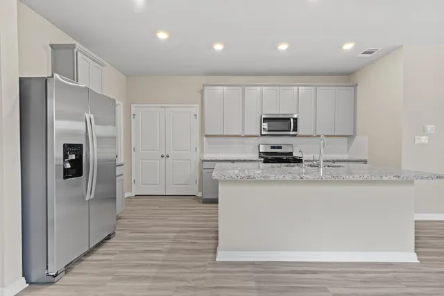 a kitchen with granite countertop a refrigerator and a stove top oven