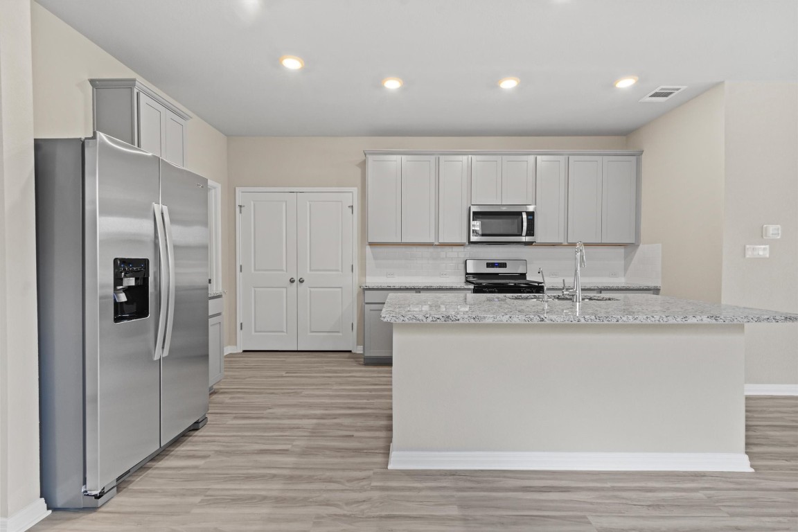 520 View Drive Georgetown, TX 78628 - Photo 2 of 23 a kitchen with granite countertop a refrigerator and a stove top oven