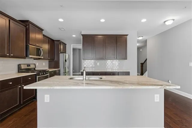 a kitchen with stainless steel appliances granite countertop a sink a stove and a refrigerator