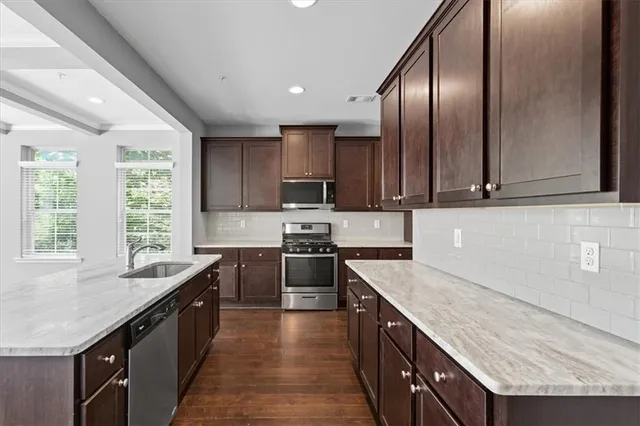 a kitchen with stainless steel appliances granite countertop a sink a stove and a refrigerator