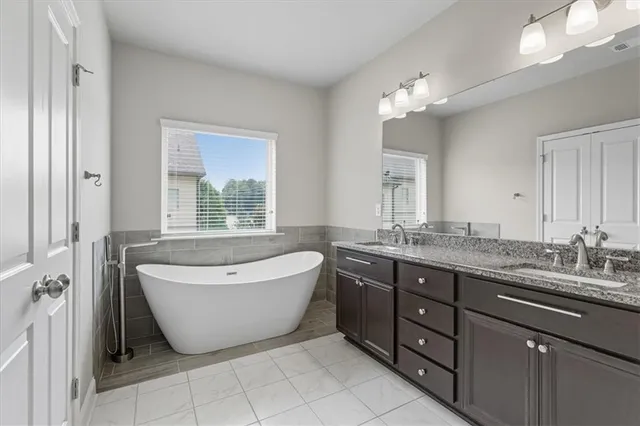 a spacious bathroom with a granite countertop tub double sink and a mirror