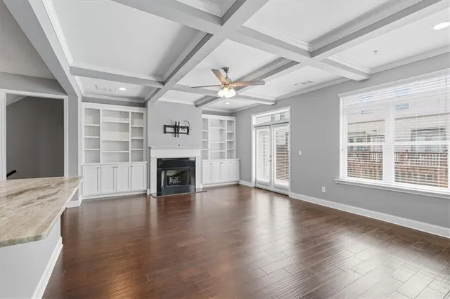 an empty room with wooden floor fireplace and windows