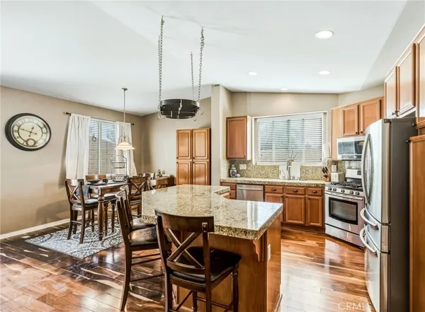 a kitchen with stainless steel appliances granite countertop a stove a refrigerator a kitchen island a table and chairs