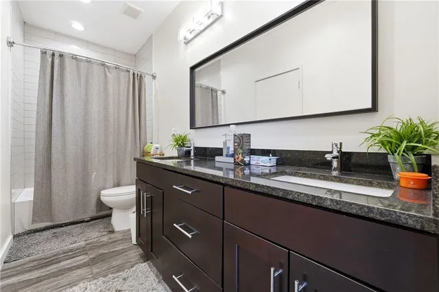 a bathroom with a granite countertop sink a toilet and a mirror