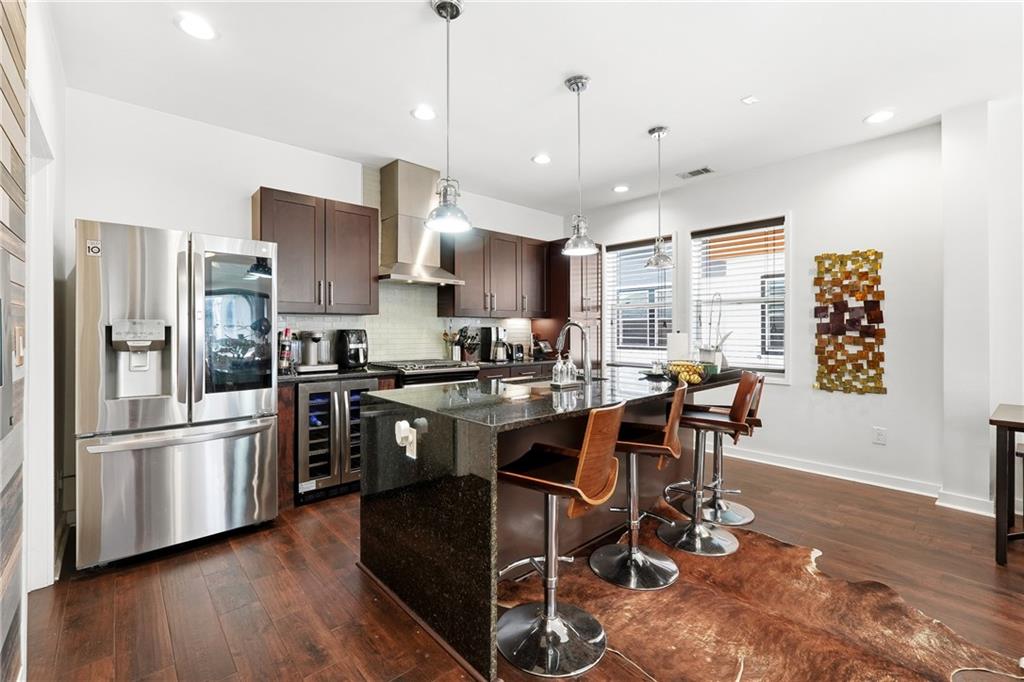 225 Crumley Street Southwest Atlanta, GA 30312 - Photo 8 of 23 a kitchen with stainless steel appliances kitchen island granite countertop a refrigerator a stove a sink a dining table and chairs with wooden floor