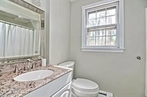 a bathroom with a granite countertop toilet a sink and a mirror
