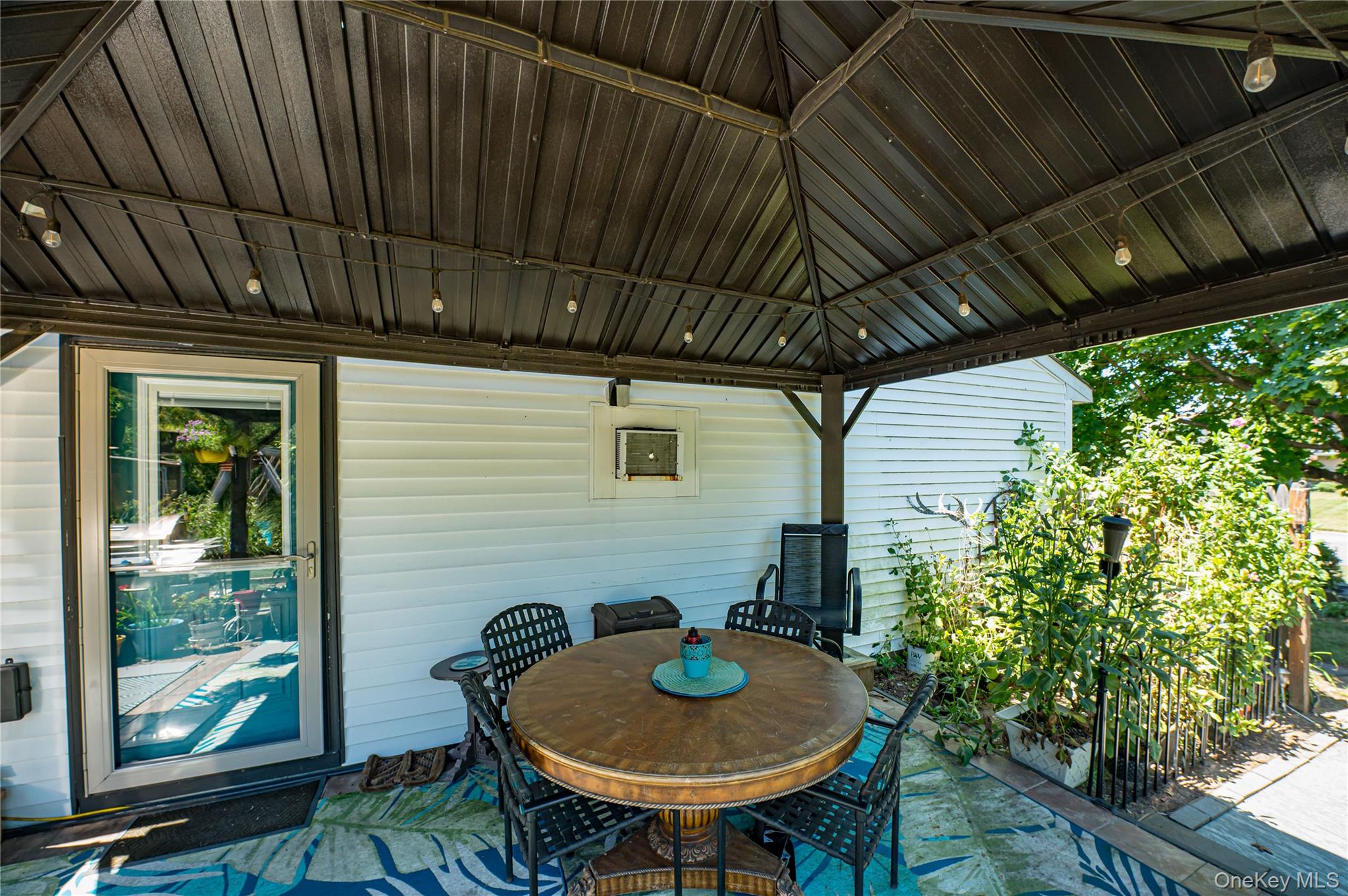 8 Woodbrook Drive, Unit 8 Ridge, NY 11961 - Photo 29 of 30 a backyard of a house with table and chairs with plants