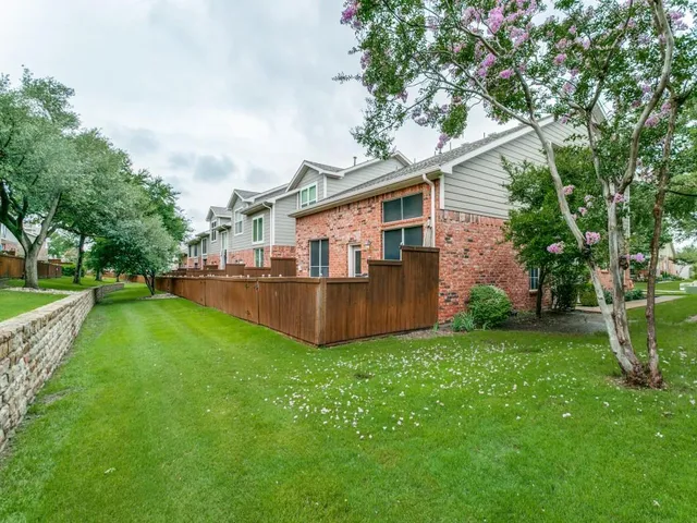 a view of a house with a big yard potted plants and large tree