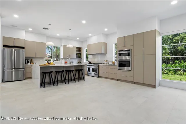 a kitchen with stainless steel appliances a refrigerator a stove a sink dishwasher with a dining table and chairs