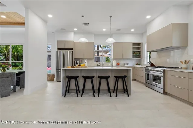 a kitchen with stainless steel appliances kitchen island granite countertop a table chairs sink and stove top oven