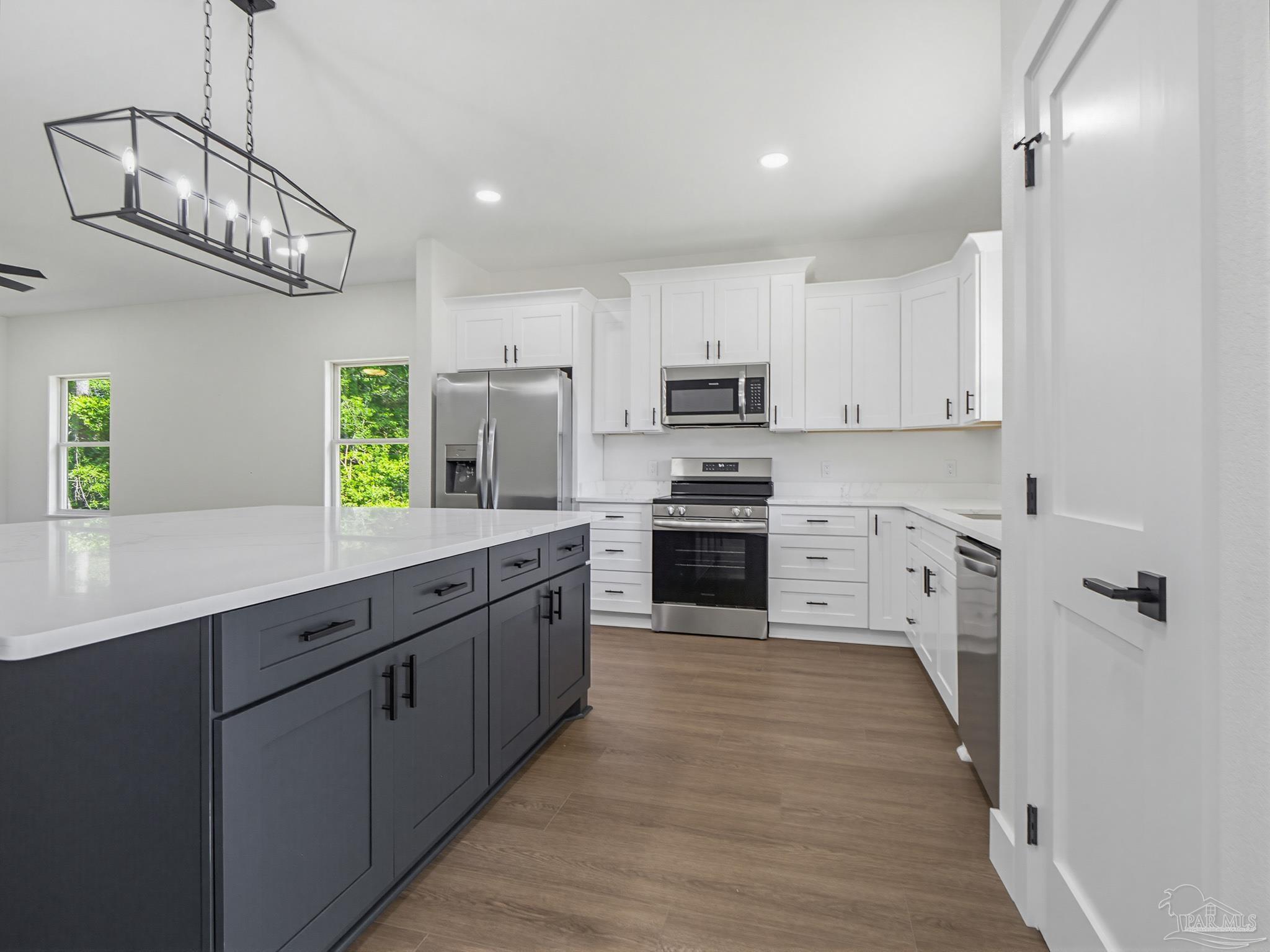 5724 Riviera Drive Milton, FL 32583 - Photo 22 of 52 a kitchen with stainless steel appliances granite countertop a sink a stove top oven a refrigerator cabinets and wooden floor