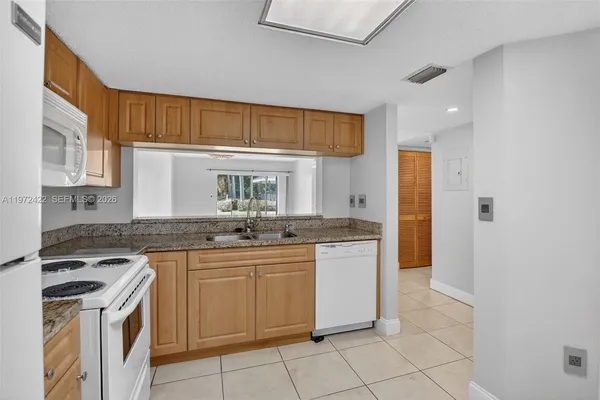 a kitchen with granite countertop a sink stove and cabinets