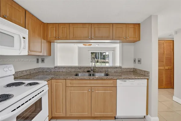 a kitchen with granite countertop a sink stove and cabinets