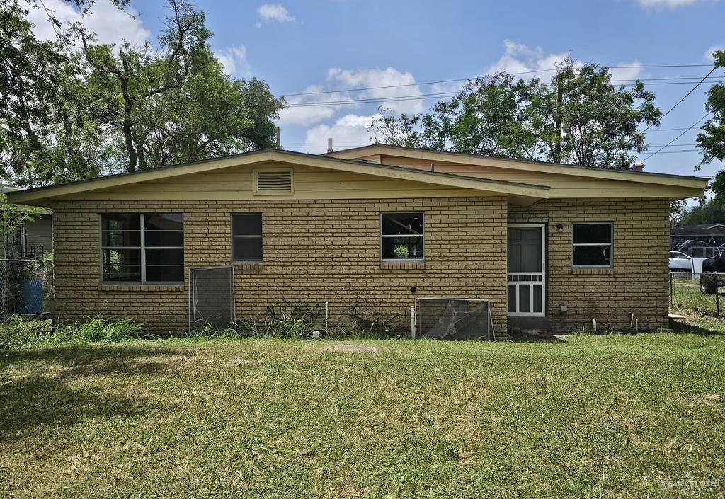 Rear view of property with a lawn and brick siding