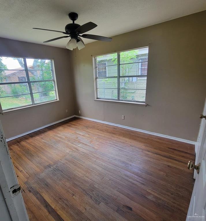 3135 Southmost Road Brownsville, TX 78521 - Photo 3 of 9 Empty room featuring hardwood / wood-style floors, a ceiling fan, baseboards, and a textured ceiling