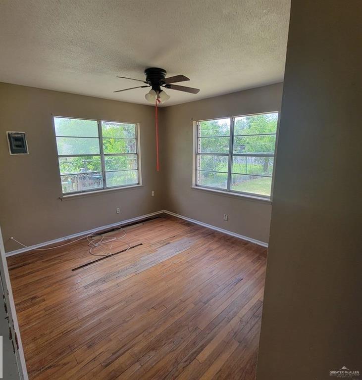 3135 Southmost Road Brownsville, TX 78521 - Photo 6 of 9 Unfurnished room with a ceiling fan, a textured ceiling, baseboards, and hardwood / wood-style floors