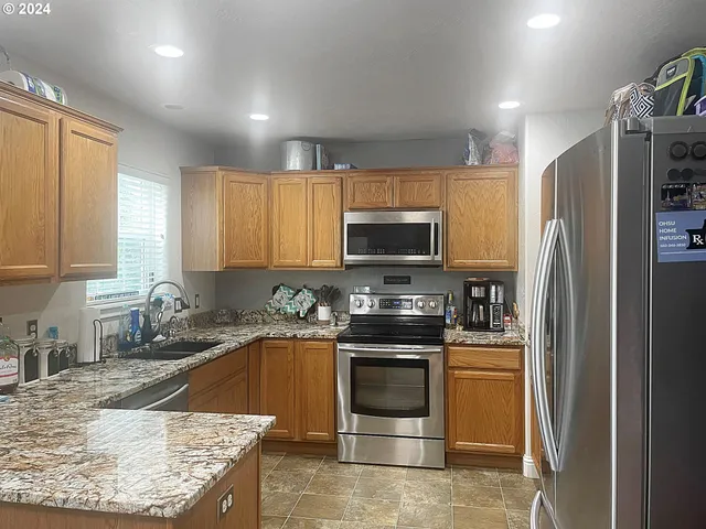 a kitchen with stainless steel appliances granite countertop a stove a sink and a microwave