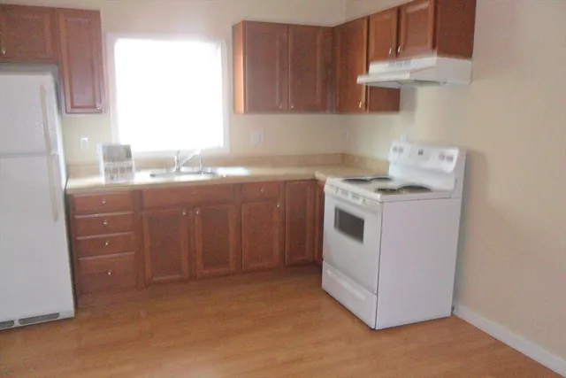 a room with a refrigerator and a wooden floor