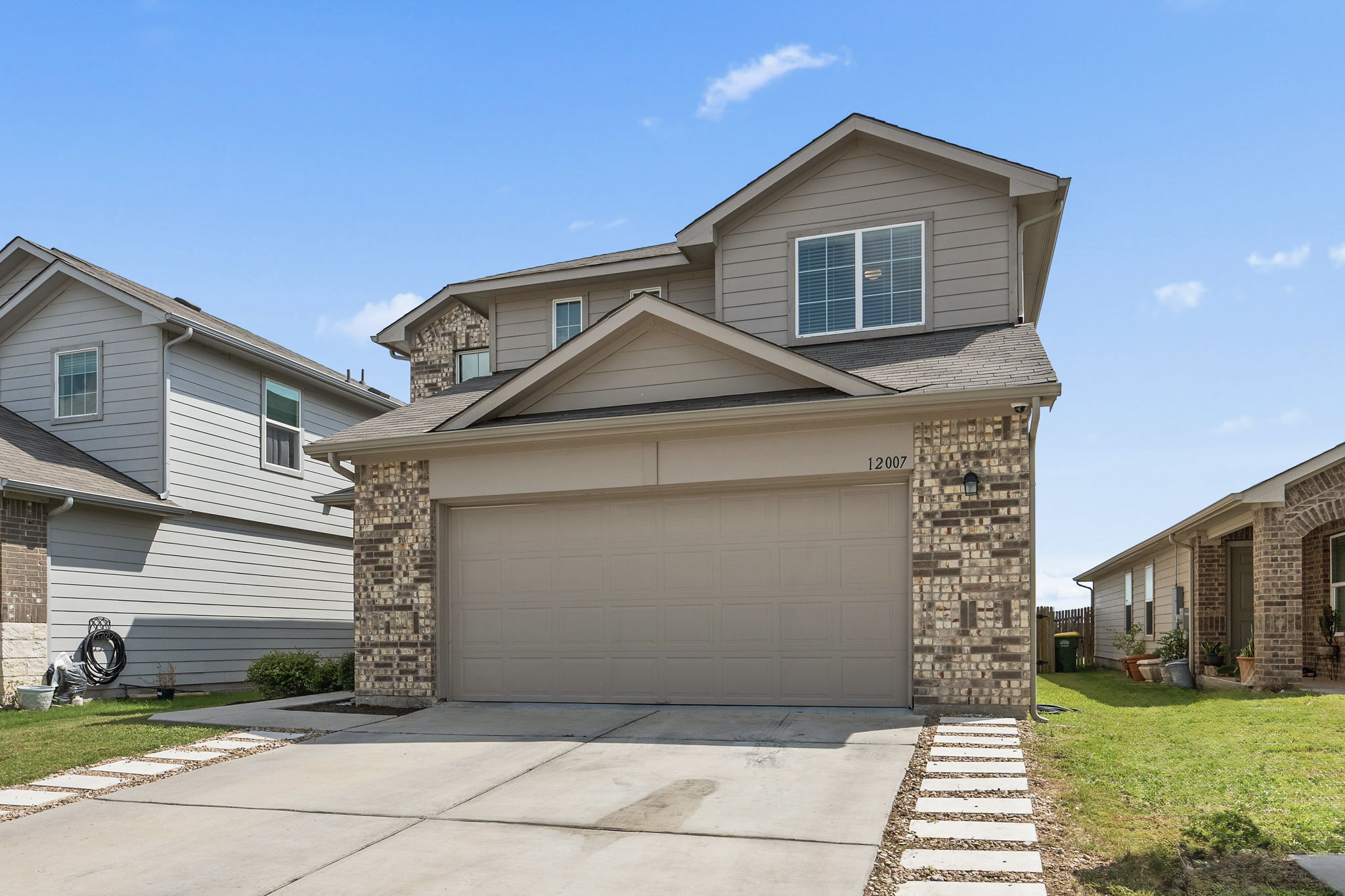 12007 Riprap Drive Manor, TX 78653 - Photo 2 of 37 A welcoming facade showcases a two-story home with a two-car garage and a paved driveway.