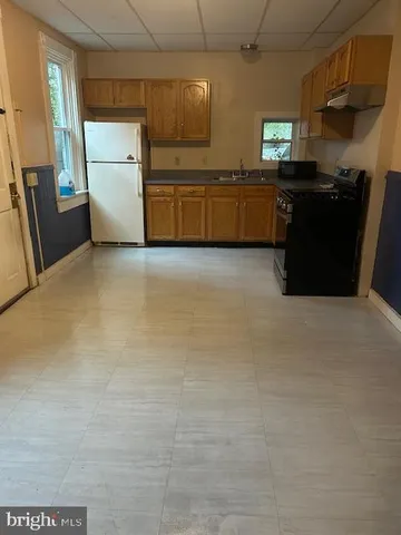 a kitchen with granite countertop a sink a stove top oven and wooden floor
