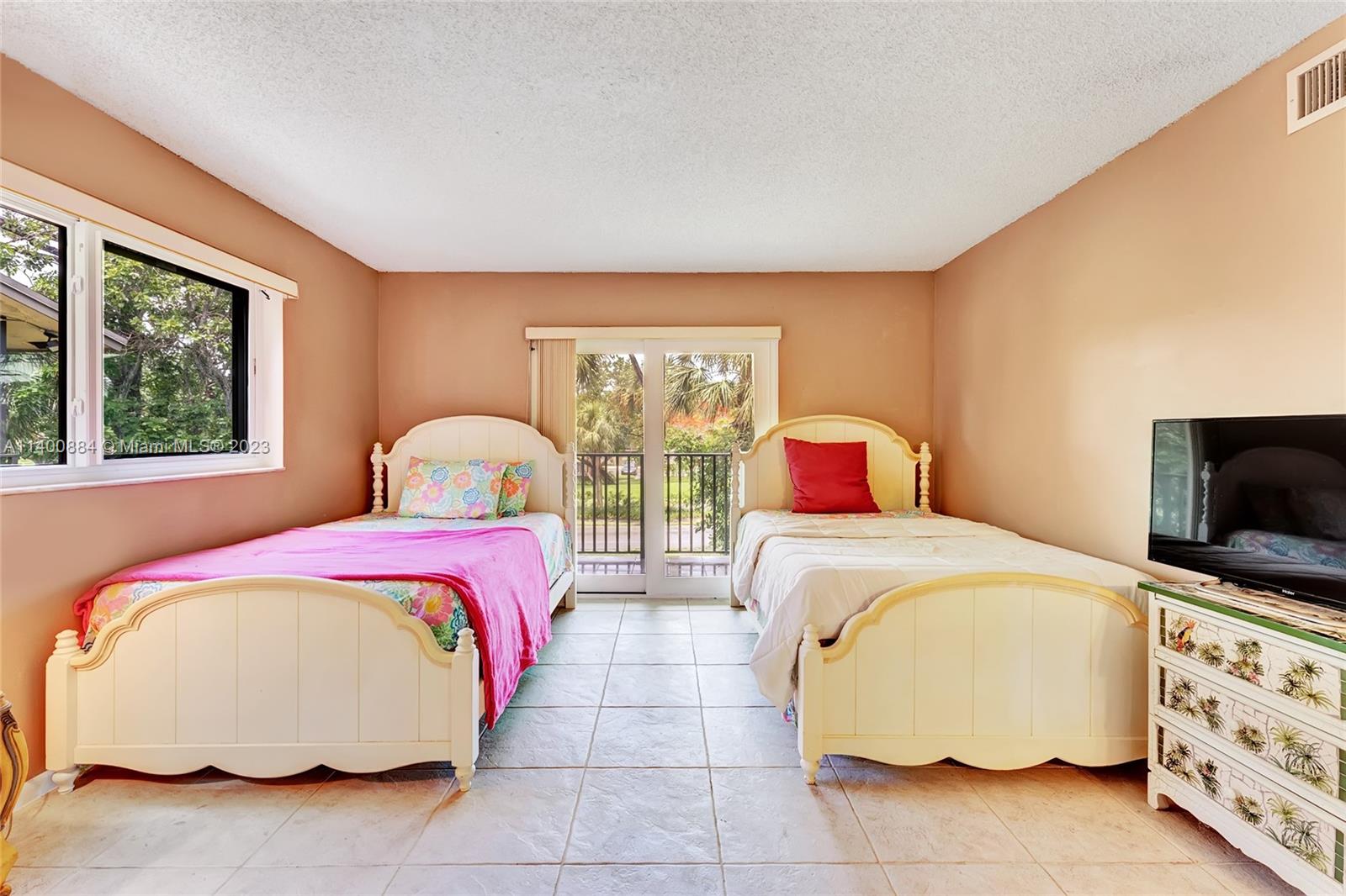 677 Trace Circle, Unit 210 Deerfield Beach, FL 33441 - Photo 9 of 21 a bedroom with a bed and a flat tv screen on dresser